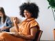 Black businesswoman smiling cheerfully while sitting in a meeting with her colleague. Happy young businesswomen working together in a modern workplace - female entrepreneurship