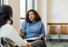 The female therapist gestures while she talks to the unrecognizeable woman about some strategies she can use at work to deescalate tough situations.