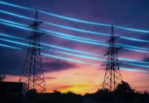 Electricity transmission towers with blue glowing wires against sunset sky background. Energy infrastructure concept.