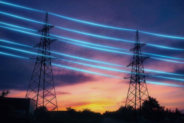 Electricity transmission towers with blue glowing wires against sunset sky background. Energy infrastructure concept.