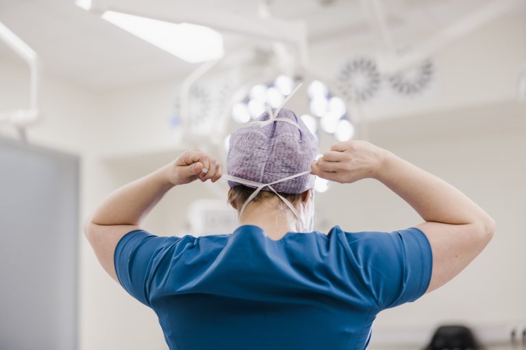 Female surgeon tying surgical mask in operation theater at hospital