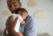 Father Holding Newborn Baby Son In Nursery