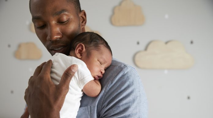 Father Holding Newborn Baby Son In Nursery