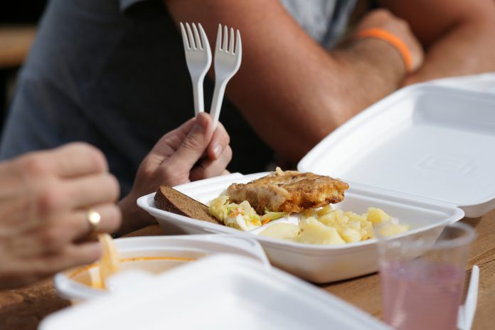 Outdoor photography of a close up of man with food in plastic container