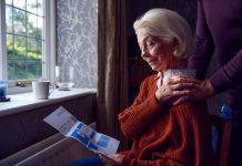 Senior Couple With USA Energy Bill Trying To Keep Warm By Radiator In Cost Of Living Energy Crisis, fuel poverty