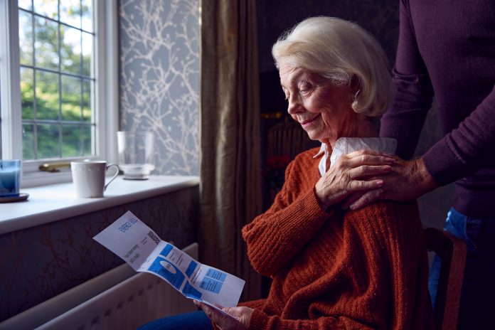 Senior Couple With USA Energy Bill Trying To Keep Warm By Radiator In Cost Of Living Energy Crisis, fuel poverty