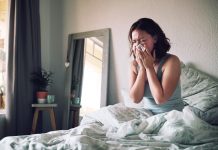 women in bed blowing nose with a cold