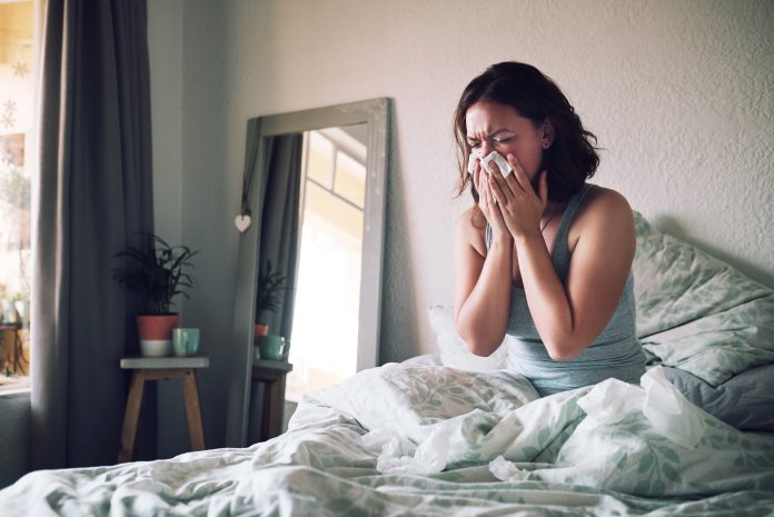 women in bed blowing nose with a cold