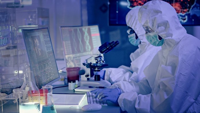 COVID-19 - multi ethnic laboratory team working on coronavirus. Level of infectivity map in background