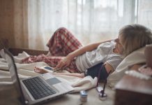 Old woman in bed looking at screen of laptop and consulting with a doctor online at home, telehealth