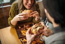 two people eating hamburgers at a restaurant