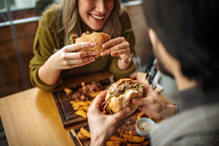 two people eating hamburgers at a restaurant