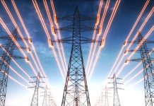 High voltage transmission towers with red glowing wires against blue sky - Energy concept