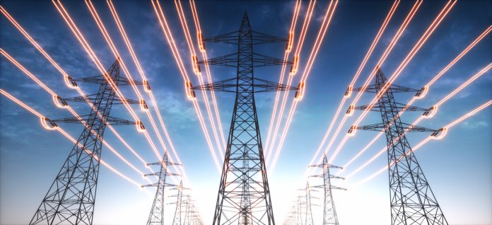 High voltage transmission towers with red glowing wires against blue sky - Energy concept