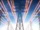 High voltage transmission towers with red glowing wires against blue sky - Energy concept