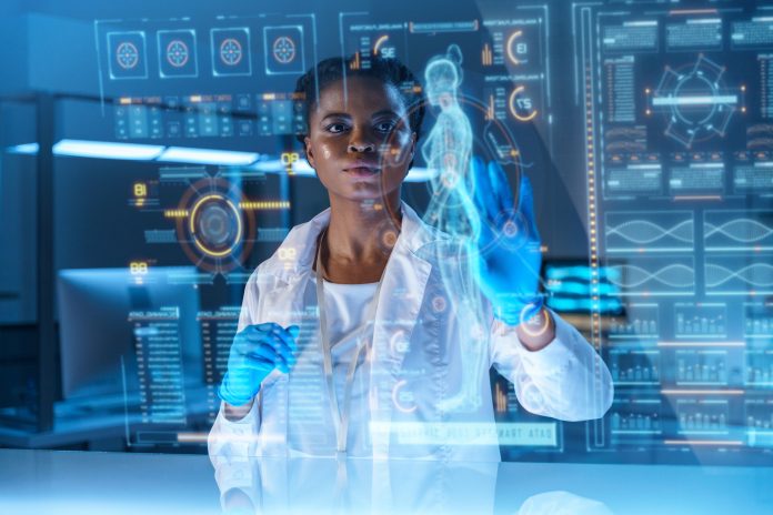 A young African - American doctor works on HUD or graphic display in front of her