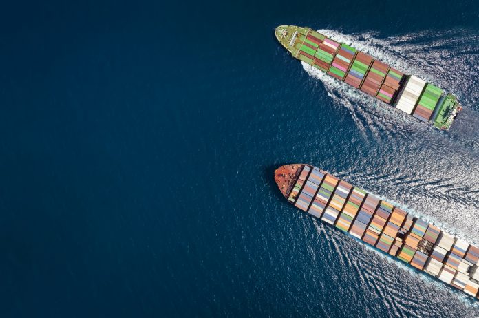 High aerial top down view of two container cargo ships traveling over open ocean with copy space as a concept for import and export industry