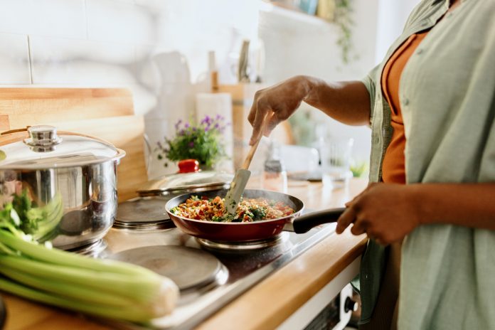 Woman preparing quinoa vegetable mix cooked in a frying pan