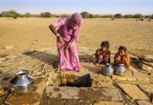 Women collecting fresh water in drought with her two young children