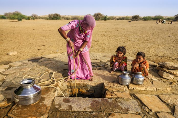 Women collecting fresh water in drought with her two young children
