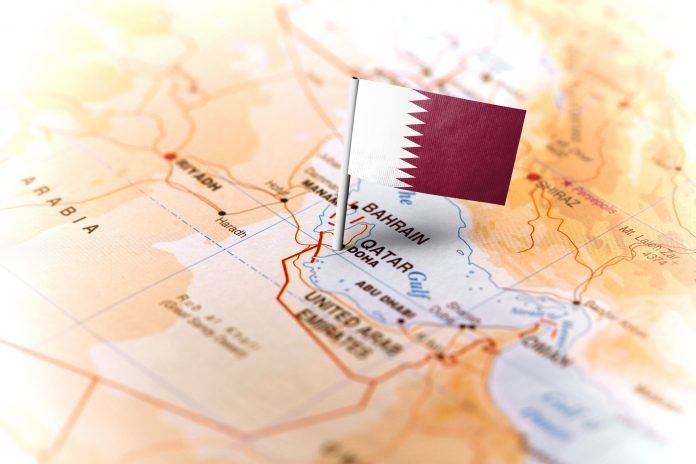 The flag of Qatar pinned on the map. Horizontal orientation. Macro photography.