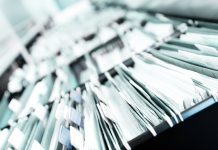 Multiple rows of filing cabinets in an office or medical establishment, overflowing with files. Narrow depth of field to emphasize the "neverending" feeling - tackling health and social care sectors and patient care