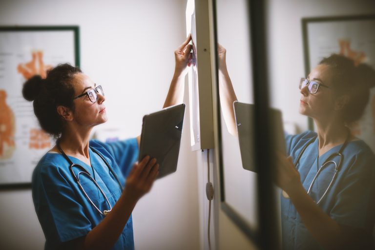 healthcare worker taking notes on white board with ipad in hand