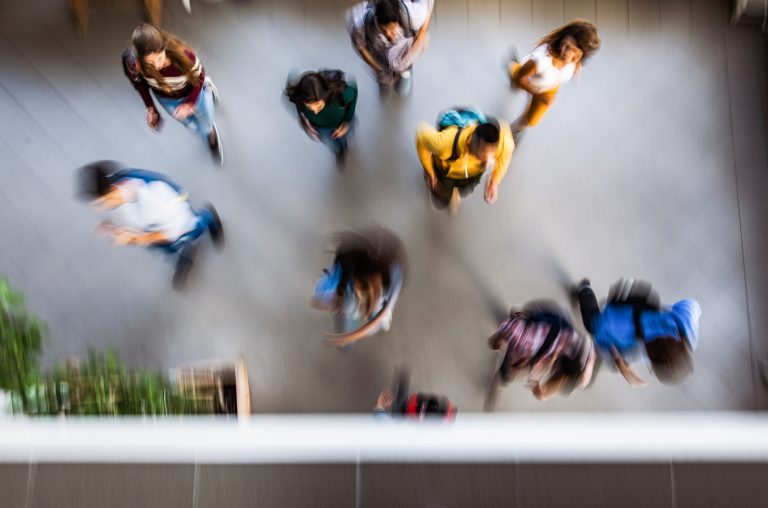 High angle view of large group of students running through the school hallway. Blurred motion.