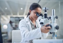 Shot of a young scientist using a microscope while conducting research in a laboratory