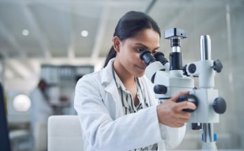 Shot of a young scientist using a microscope while conducting research in a laboratory