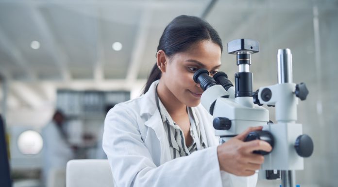 Shot of a young scientist using a microscope while conducting research in a laboratory