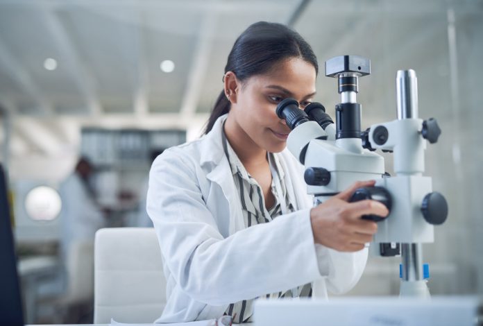 Shot of a young scientist using a microscope while conducting research in a laboratory