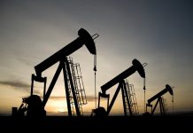 A royalty free image from the oil industry of three pumpjacks on a prairie at sunrise.