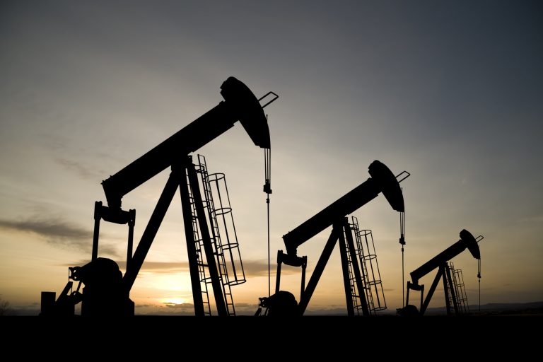 A royalty free image from the oil industry of three pumpjacks on a prairie at sunrise.