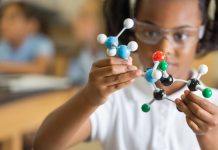 Elementary science student using plastic atom model educational toy