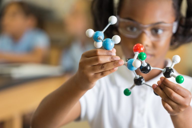 Elementary science student using plastic atom model educational toy