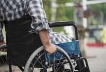 Close-up of senior woman hand on wheel of wheelchair during walk in hospital