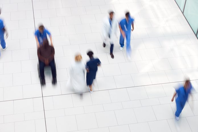 Overhead View Of Medical Staff Walking Through Lobby Of Modern Hospital Building With Motion Blur