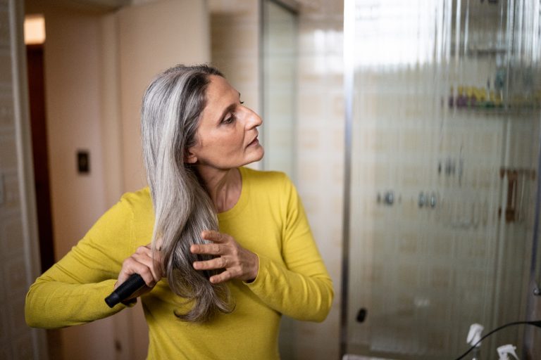 Mature woman brushing her hair at home