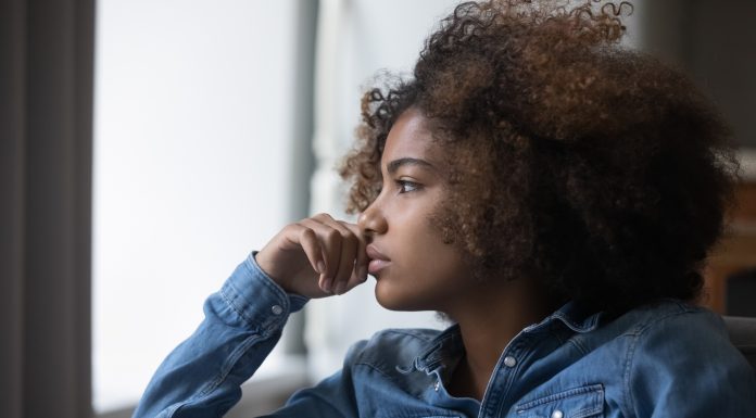 Close up side profile view face of African sad thoughtful teenager girl sit on sofa at home looking into distance feels unhappy, first unrequited love, teen relation problem, break up, worries concept