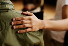 Hand of young supportive man consoling his friend or one of attendants with post traumatic syndrome caused by dramatic life event