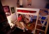 High angle view at two young students doing homework together sitting on bunk bed and in college dorm, copy space