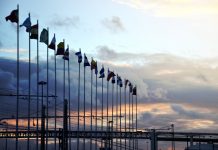 International flags on industrial background at sunset. Global warming and united nations concept.