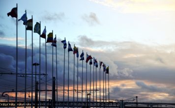 International flags on industrial background at sunset. Global warming and united nations concept.