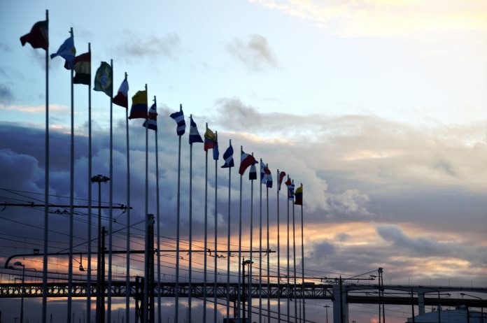 International flags on industrial background at sunset. Global warming and united nations concept.