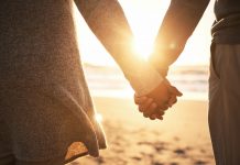 couple holding hands with sunset in background