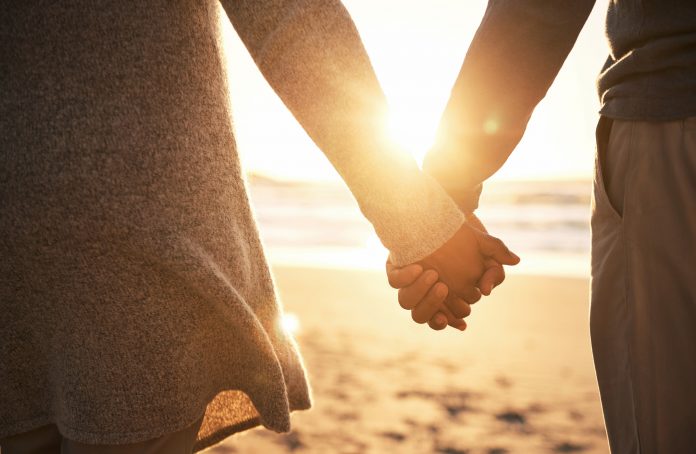 couple holding hands with sunset in background
