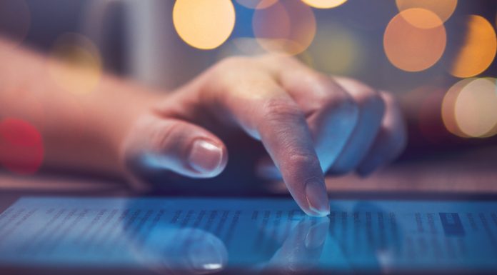 Woman reading online news on digital tablet, close up of hands using device, text-to-speech learning