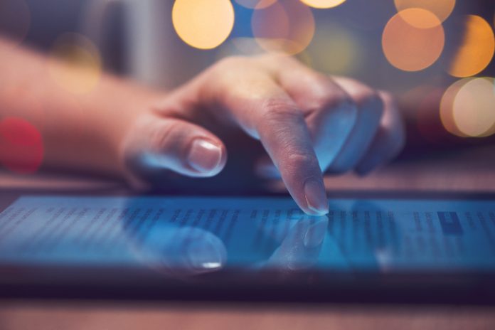 Woman reading online news on digital tablet, close up of hands using device, text-to-speech learning