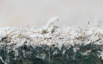 Detailed photography of constructional material with asbestos fibres. Health harmful and hazards effects. Prolonged inhalation of microscopical fibers causes fatal illnesses including lung cancer.